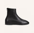 A single black leather ankle boot with a side zipper, shown in profile against a light cream background.