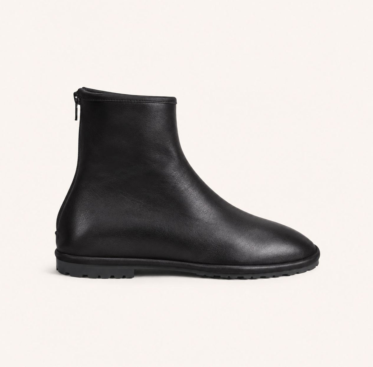 A single black leather ankle boot with a side zipper, shown in profile against a light cream background.