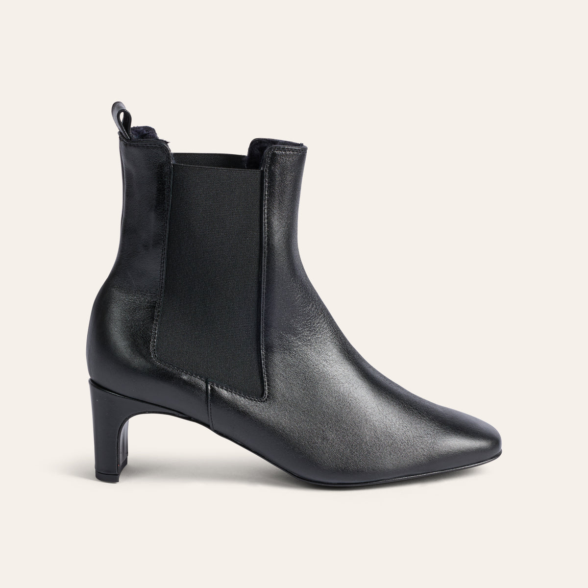 A single black leather ankle boot with a mid-height block heel and elastic side gore, shown in profile against a light cream background.