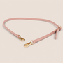 Pink shoulder strap with gold hardware on a beige background
