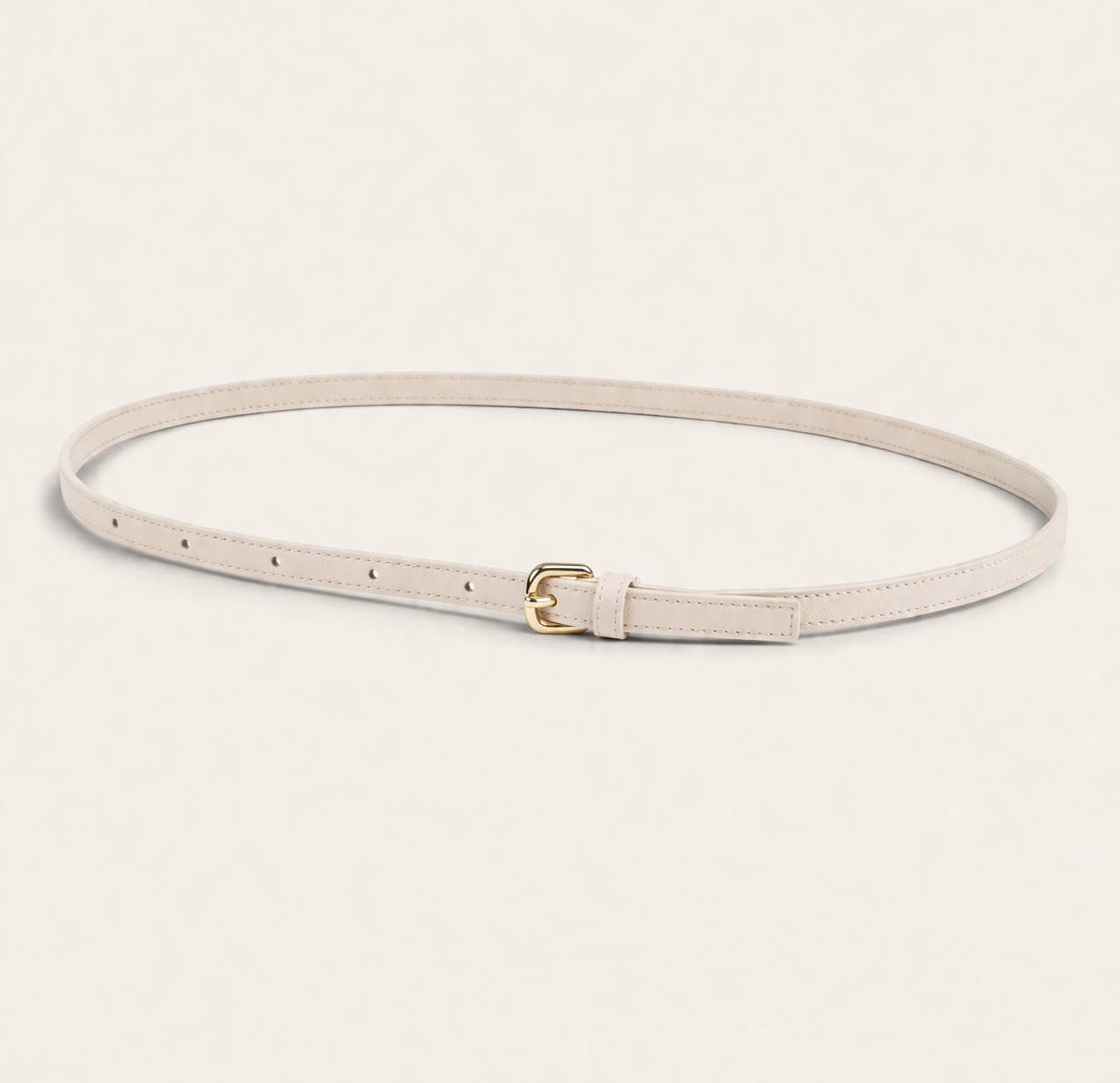 Thin ivory belt with a gold buckle on a light beige background