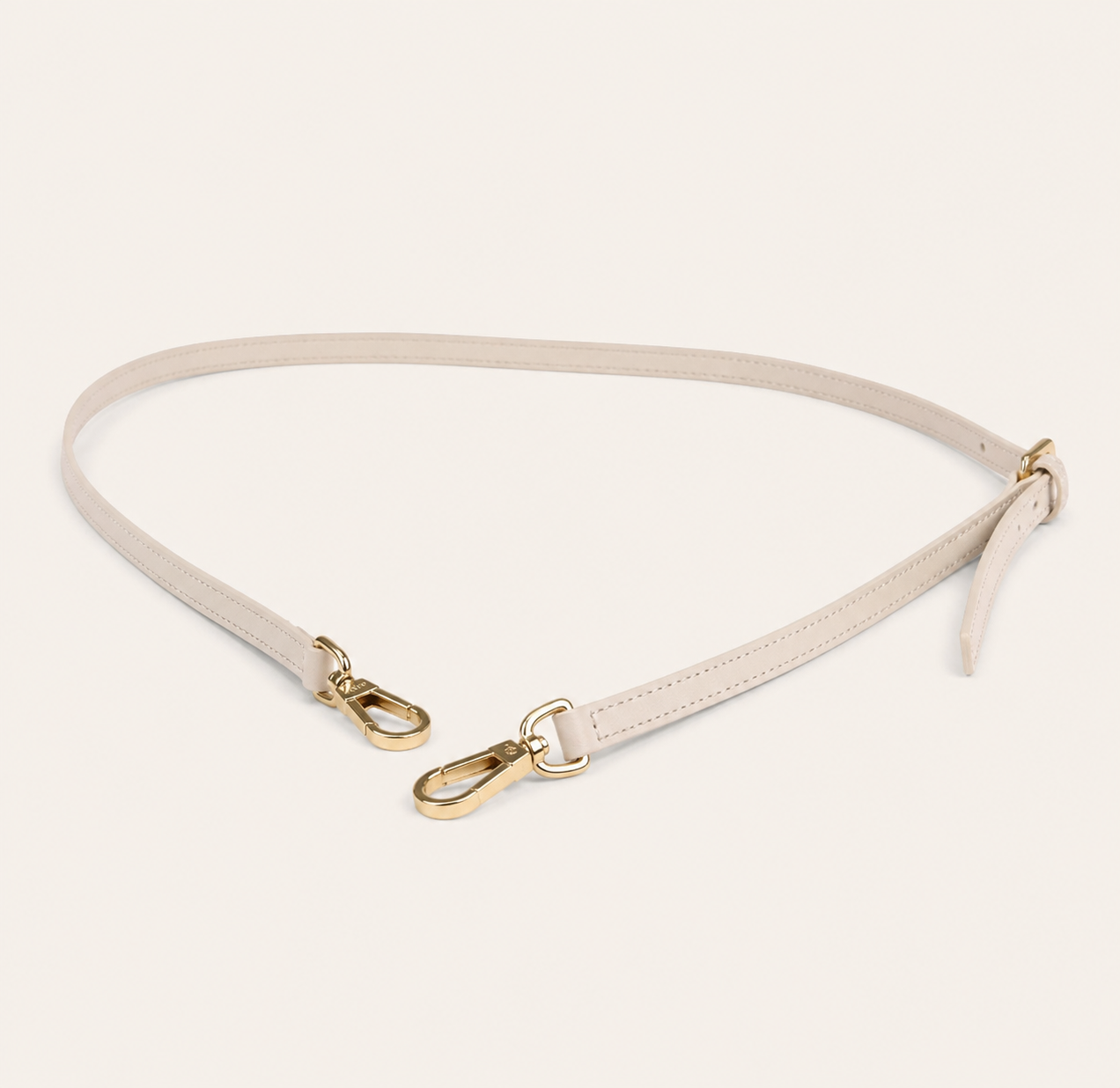 Ivory belt with gold hardware on a light beige background