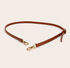 Brown leather shoulder strap with gold hardware on a beige background