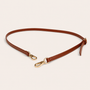 Brown leather shoulder strap with gold hardware on a beige background