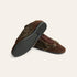 A pair of brown suede and faux-fur slip-on shoes with dark gray textured soles, shown on a light cream background.