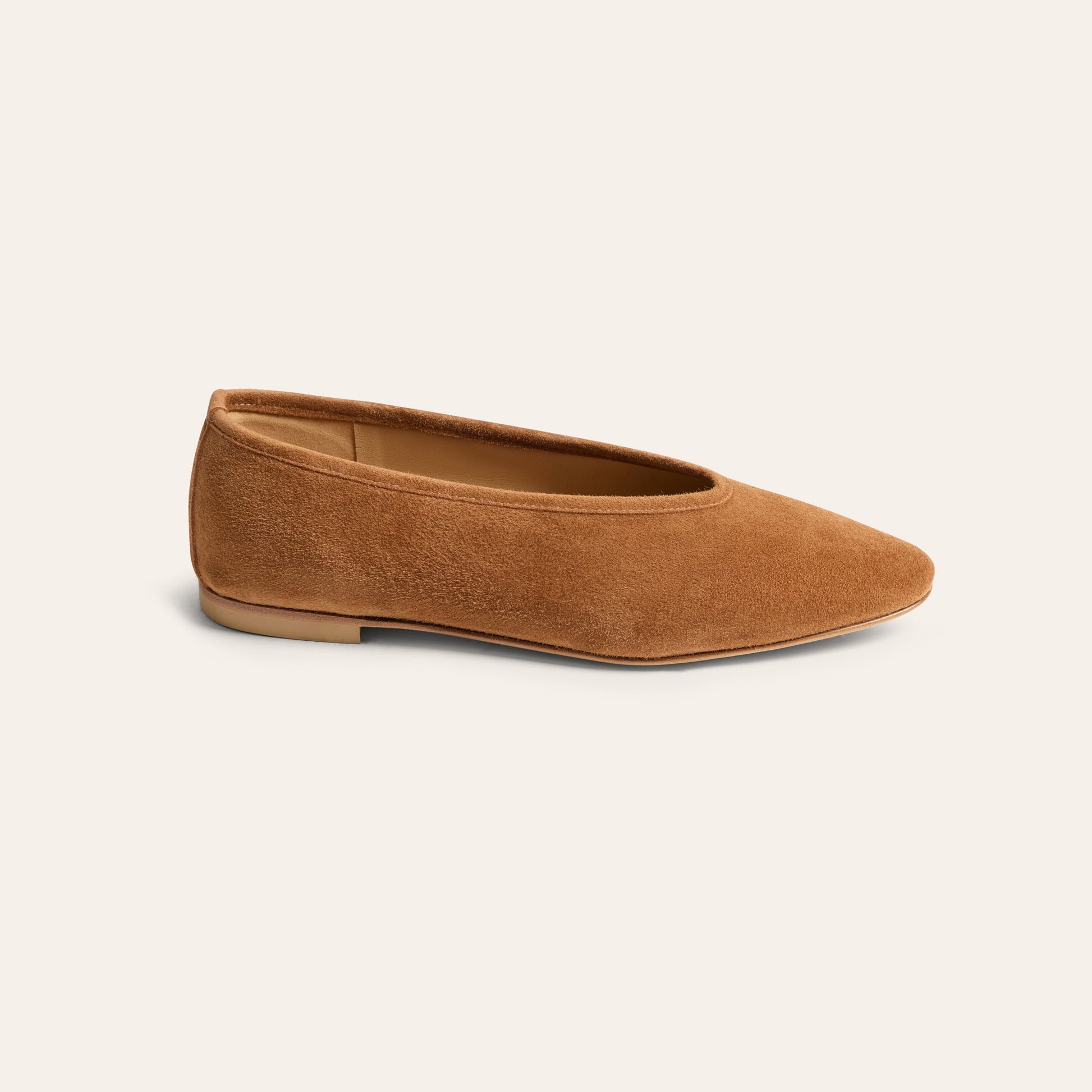 A single tan suede flat shoe with a pointed toe, shown in a side profile on a light cream background.