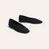 A pair of black pointed-toe flats made of soft suede, shown from different angles on a light cream background.