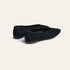 A pair of black suede flat shoes with pointed toes, shown from a three-quarters angle on a light cream background.