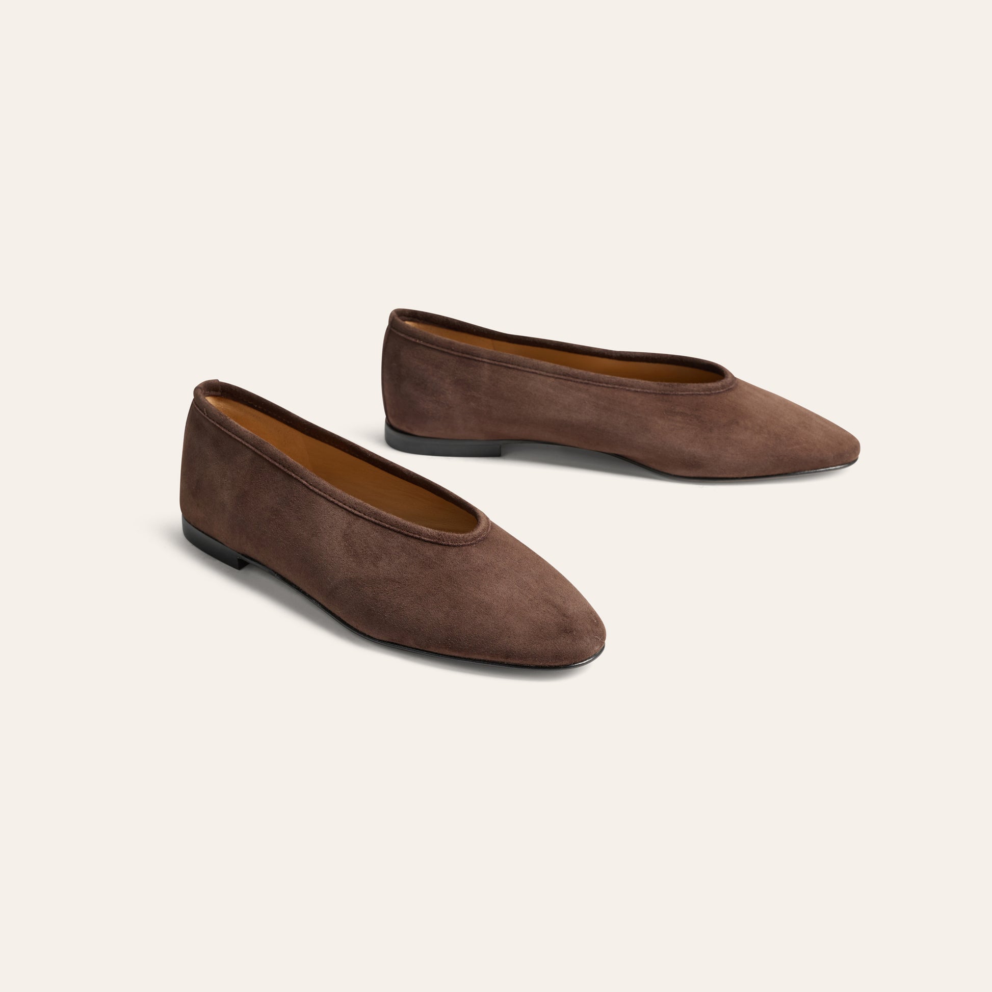 A pair of women's pointed-toe flats in dark brown suede, shown from a three-quarters angle on a light cream background.
